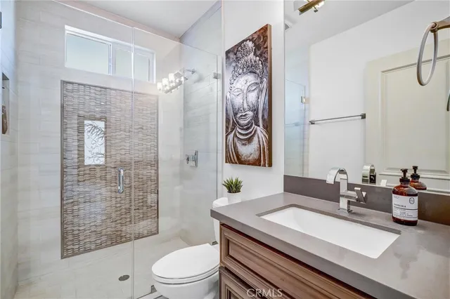 a bathroom with a granite countertop sink a toilet a mirror and shower