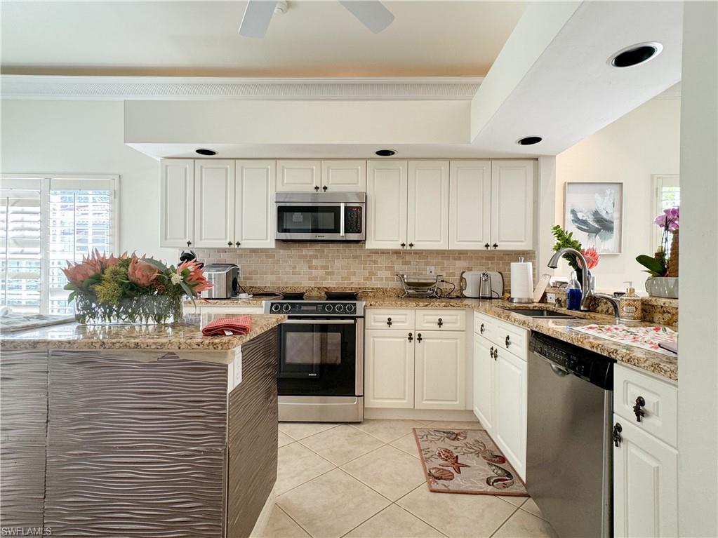 152 Napa Ridge Way Naples, FL 34119 - Photo 42 of 50 a kitchen with kitchen island granite countertop a stove sink microwave and cabinets