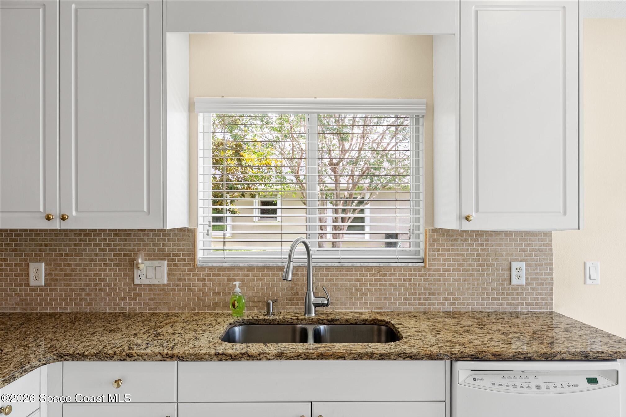 6904 Renshaw Drive Melbourne, FL 32940 - Photo 8 of 46 a kitchen with granite countertop a sink and white cabinets