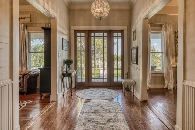 a hall way with wooden floor and a chandelier