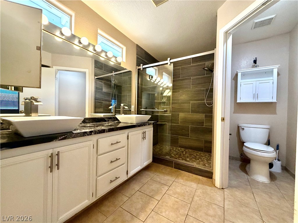 3936 Gold Point Street Las Vegas, NV 89129 - Photo 11 of 23 Dual vessel sinks and a tiled shower create a refreshing private bath retreat.