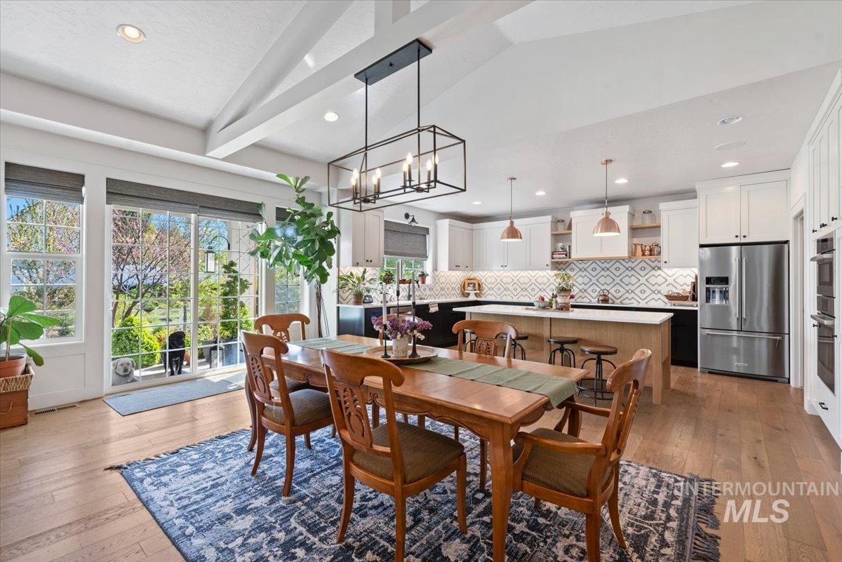 15164 Pinehurst Way Caldwell, ID 83607 - Photo 12 of 50 Open-concept kitchen and dining area featuring light wood-finish flooring, a vaulted ceiling with exposed beams, and a black framed chandelier