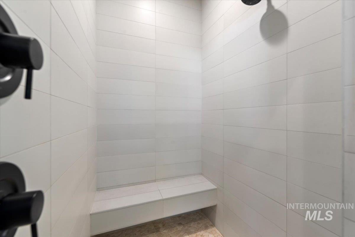 15164 Pinehurst Way Caldwell, ID 83607 - Photo 27 of 50 Shower enclosure featuring white horizontal subway tile, matte black fixtures, a built-in bench, and pebble-finish flooring