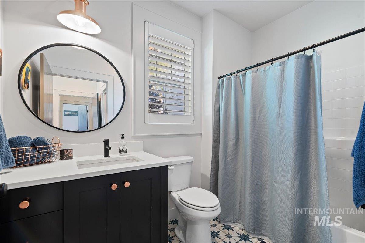 15164 Pinehurst Way Caldwell, ID 83607 - Photo 31 of 50 Bathroom featuring a white subway tile shower, patterned floor tiles, and a vanity with a white countertop and dark cabinetry
