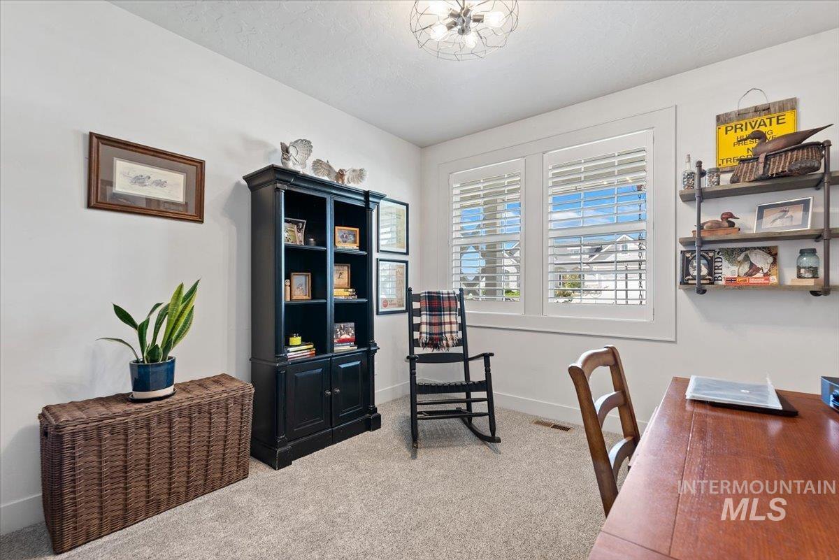 15164 Pinehurst Way Caldwell, ID 83607 - Photo 32 of 50 Carpeted room featuring dual windows with plantation shutters, a contemporary ceiling light fixture, a built-in black bookcase, and a wall-mounted shelving unit