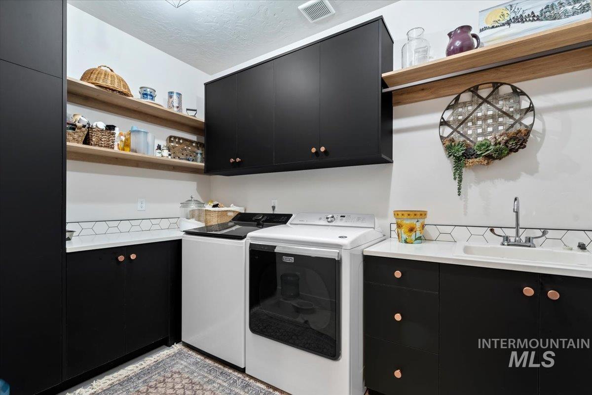 15164 Pinehurst Way Caldwell, ID 83607 - Photo 37 of 50 Laundry area featuring black cabinetry with copper-toned hardware, white countertops, and a white hexagonal tile backsplash
