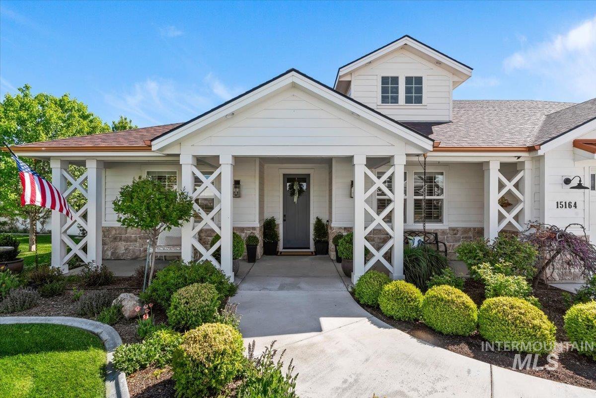 15164 Pinehurst Way Caldwell, ID 83607 - Photo 4 of 50 Craftsman-style exterior featuring white siding, a stone facade, a covered entry porch with decorative cross bracing, and a dormer with double windows