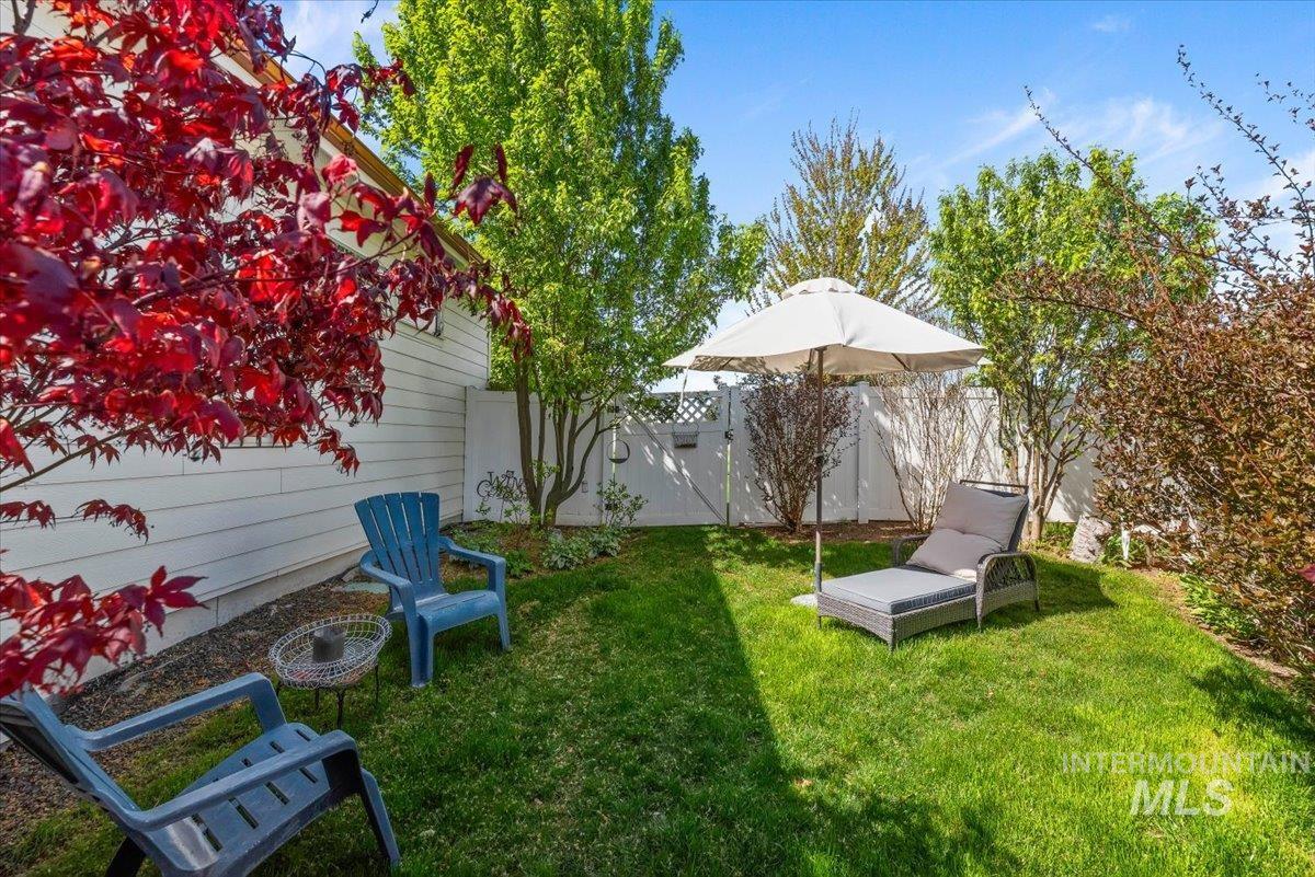 15164 Pinehurst Way Caldwell, ID 83607 - Photo 45 of 50 Private backyard area featuring a white privacy fence, mature landscaping, and a well-maintained lawn