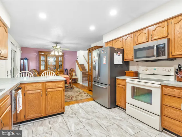 a kitchen with stainless steel appliances granite countertop a refrigerator a stove top oven a sink dishwasher and white cabinets with wooden floor