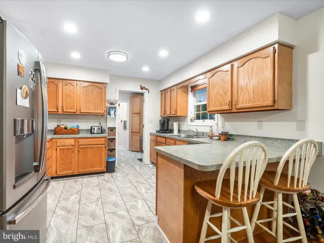 a kitchen with stainless steel appliances granite countertop a stove a sink dishwasher and a refrigerator with wooden cabinets