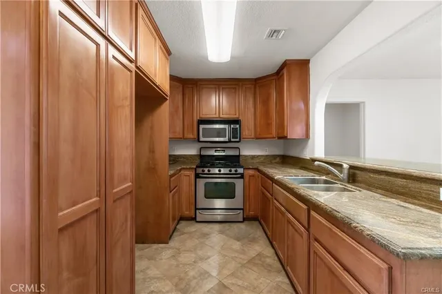 a kitchen with granite countertop stainless steel appliances a refrigerator and a sink