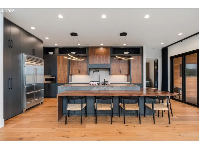 a kitchen with stainless steel appliances granite countertop a table chairs refrigerator and sink