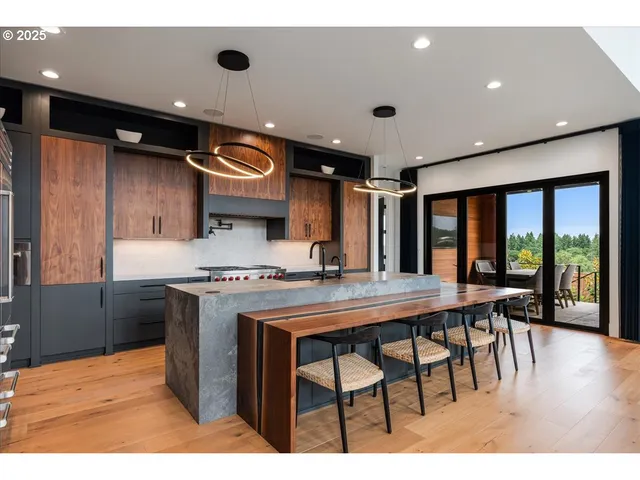 a kitchen with stainless steel appliances granite countertop a stove a refrigerator a dining table and chairs with wooden floor