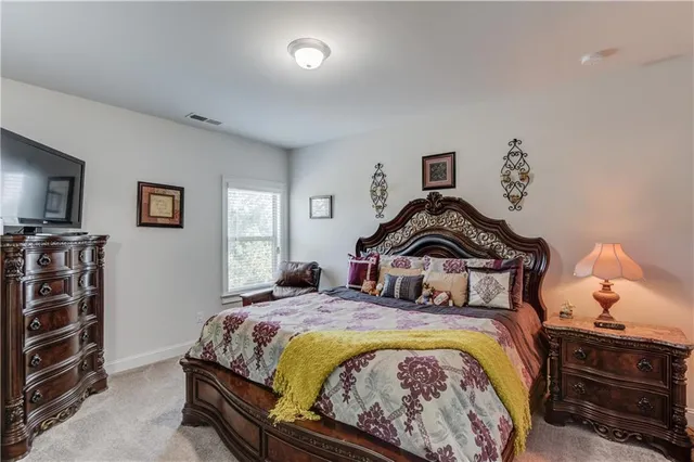 a bedroom with a bed and a lamp on dresser