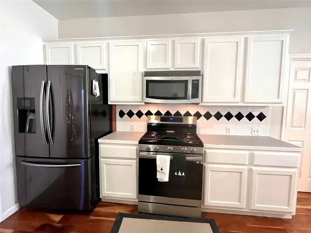 a kitchen with granite countertop white cabinets and stainless steel appliances