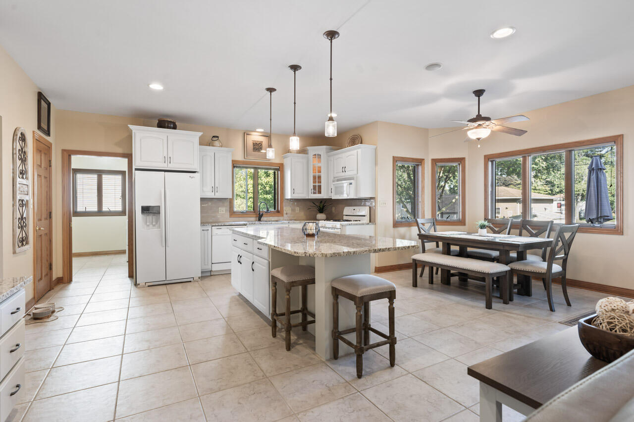 205 North Elgin Street Griffith, IN 46319 - Photo 16 of 43 a kitchen with stainless steel appliances kitchen island granite countertop a refrigerator a stove a dining table and chairs with wooden floor