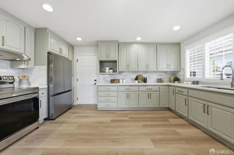 a kitchen with stainless steel appliances a refrigerator sink and white cabinets