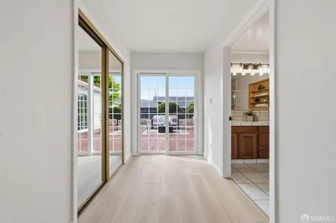 a view of a hallway with wooden floor and a living room