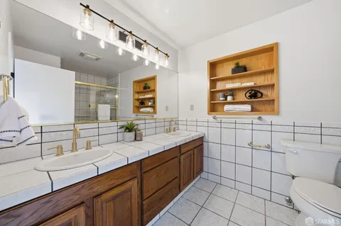a bathroom with a double vanity sink a mirror and a toilet