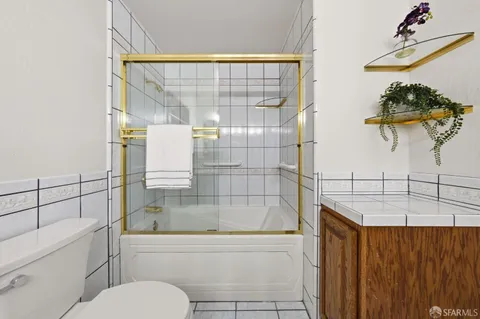 a bathroom with a granite countertop sink a toilet and shower
