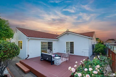 a backyard of a house with wooden table and sofas