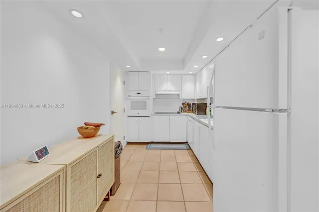 a kitchen with a refrigerator and white cabinets