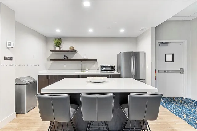 a kitchen with stainless steel appliances a table chairs and refrigerator