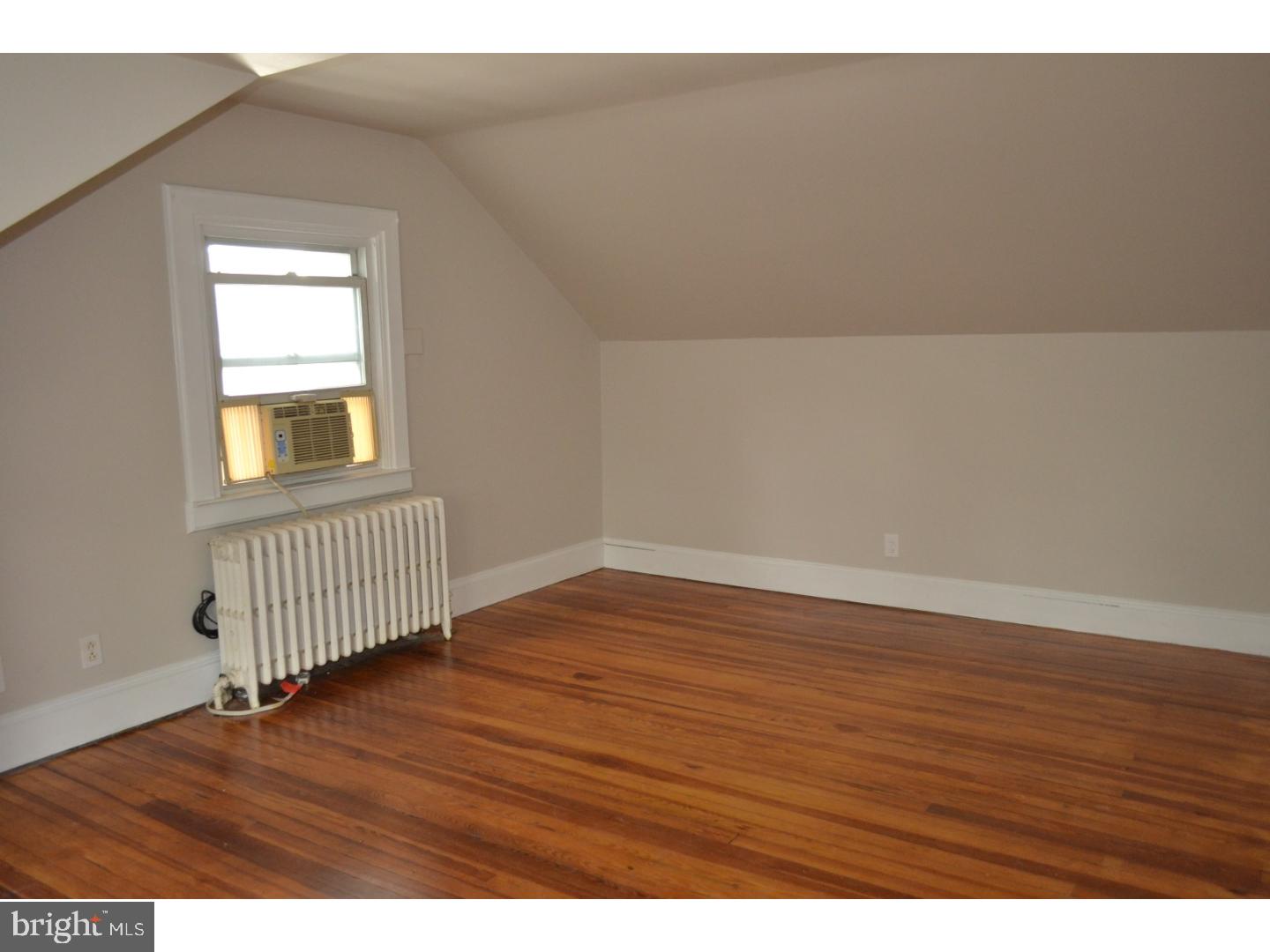 129 Walsh Road Lansdowne, PA 19050 - Photo 20 of 25 a view of an empty room with wooden floor and a window