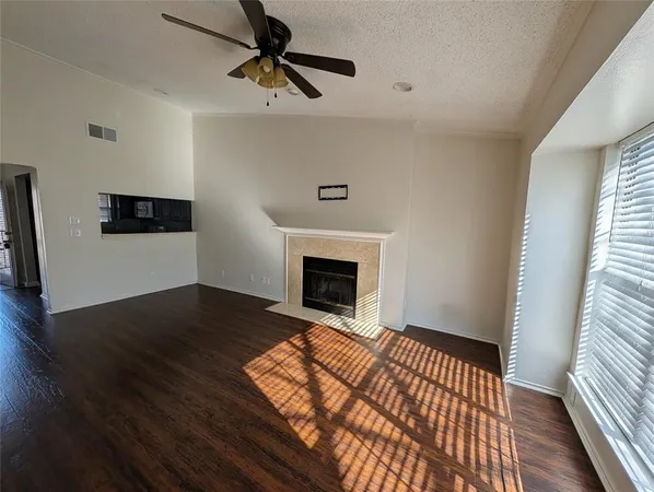 a view of an empty room with wooden floor fireplace and a window