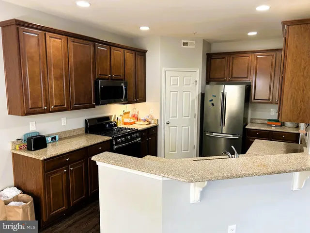 a kitchen with granite countertop a refrigerator and a stove top oven