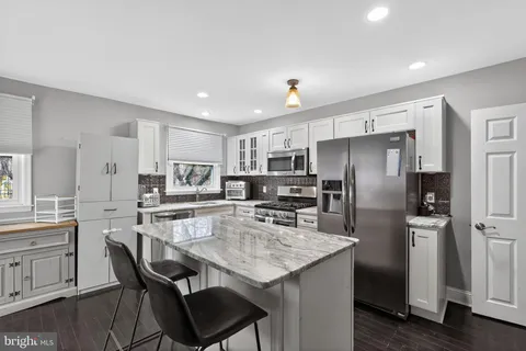 a kitchen with stainless steel appliances a dining table chairs refrigerator and cabinets