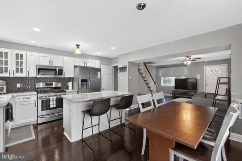 a kitchen with stainless steel appliances granite countertop a stove top oven a sink dishwasher a dining table and chairs with wooden floor