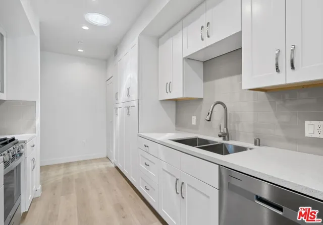 a kitchen with stainless steel appliances granite countertop a sink and white cabinets