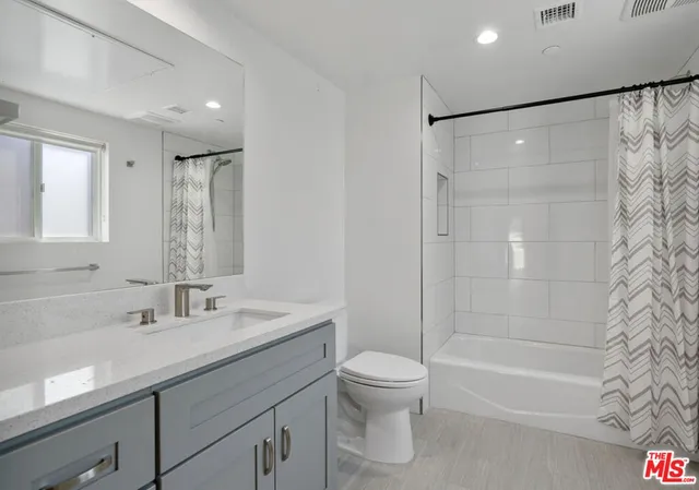 a bathroom with a shower sink vanity mirror and toilet
