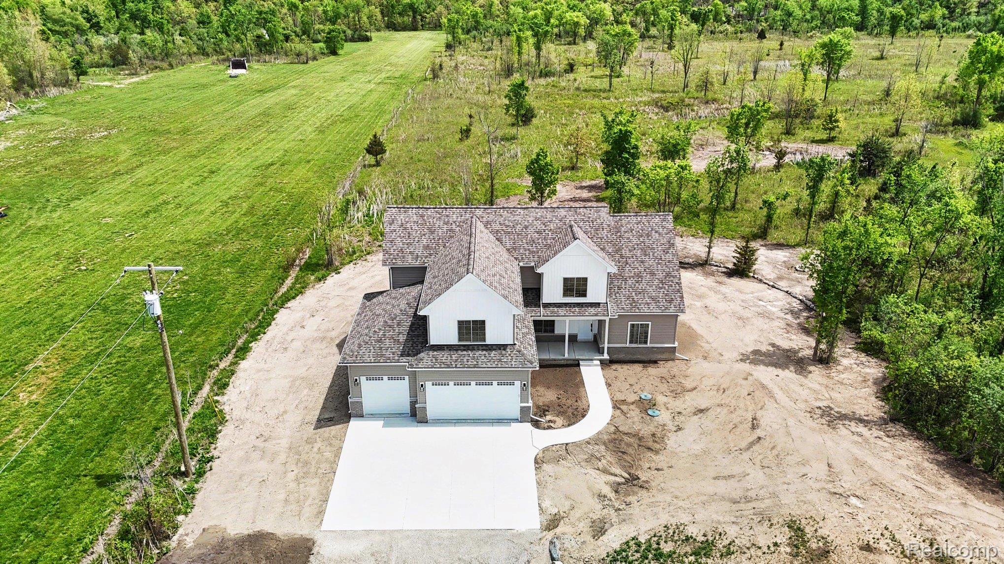 57560 Omo Road Ray, MI 48096 - Photo 38 of 44 Newly constructed residence featuring a three-car garage, concrete driveway, and a covered front porch