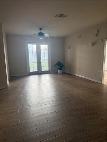 an empty room with wooden floor and windows