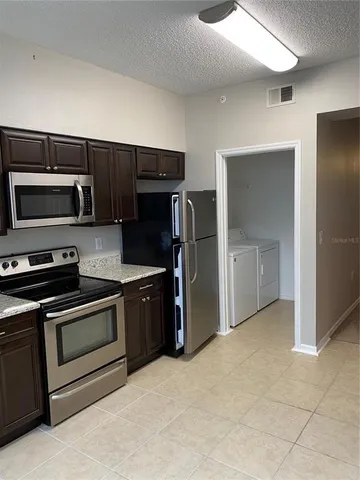 a kitchen with stainless steel appliances granite countertop a refrigerator and a stove top oven