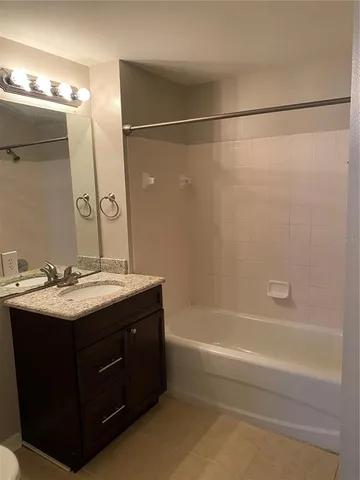 a bathroom with a granite countertop sink mirror and a bathtub