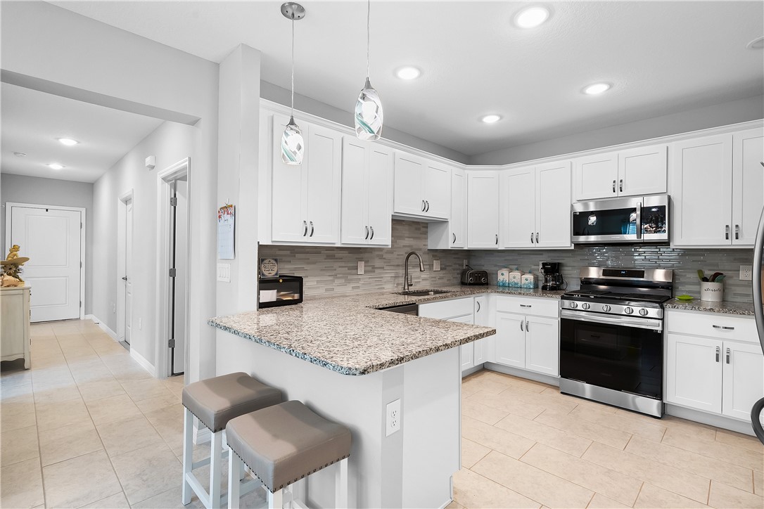 6187 Red Maple Manor Vero Beach, FL 32966 - Photo 6 of 31 a kitchen with kitchen island granite countertop a stove sink microwave and cabinets