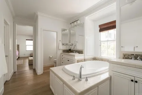a spacious bathroom with a tub sink and mirror