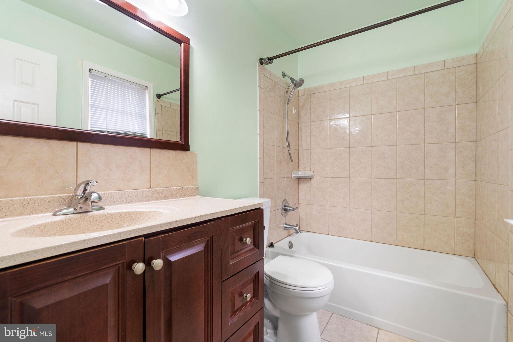 9301 Bellbeck Road Baltimore, MD 21234 - Photo 21 of 35 a bathroom with a granite countertop sink a toilet a mirror and bathtub