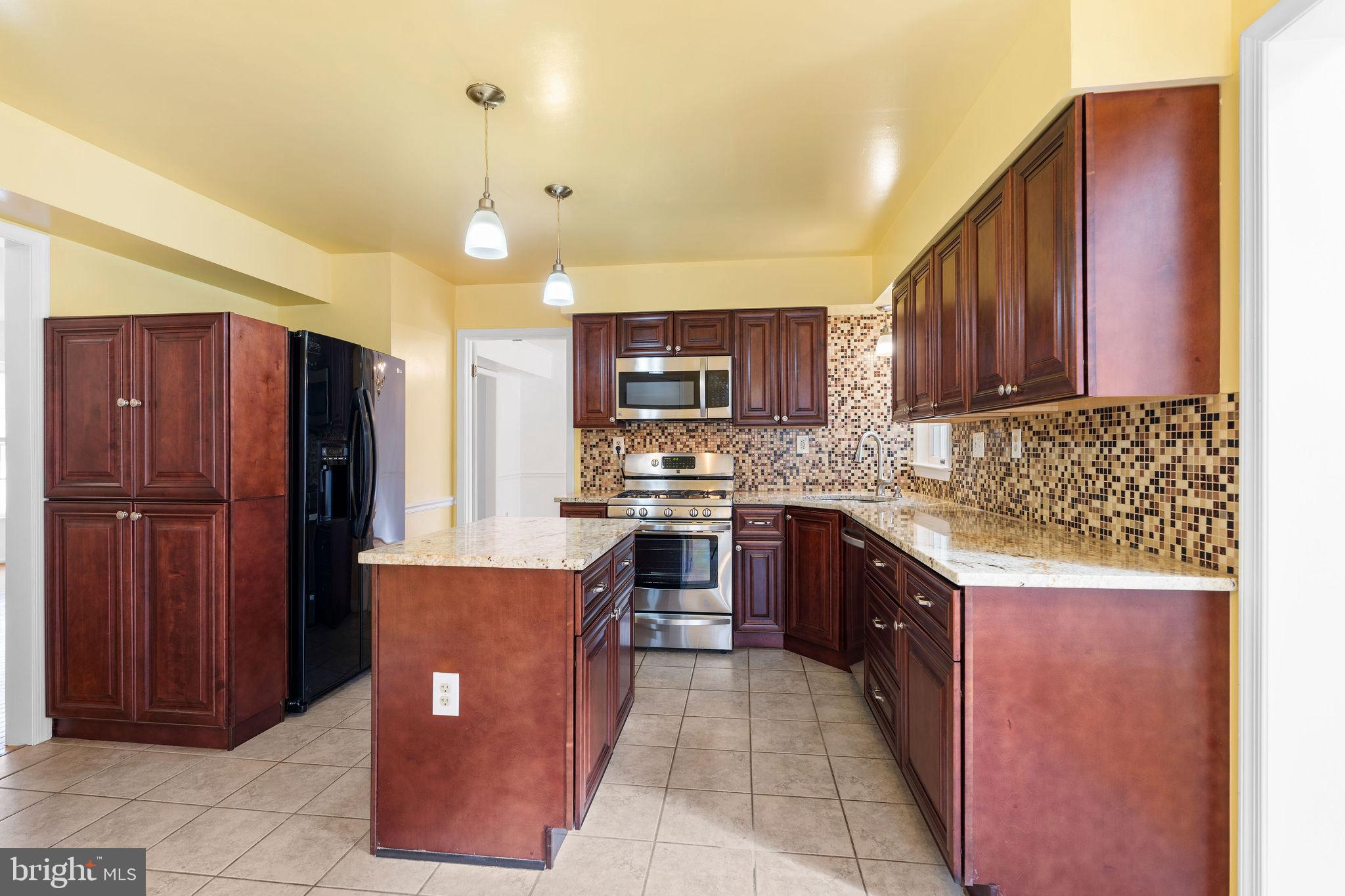 9301 Bellbeck Road Baltimore, MD 21234 - Photo 8 of 35 a large kitchen with stainless steel appliances granite countertop wooden cabinets a stove a sink and a refrigerator