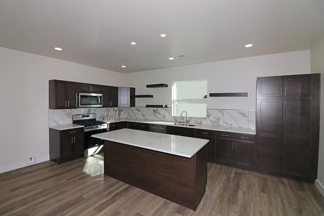 2459 Ross Road Grand Junction, CO 81505 - Photo 8 of 29 a large kitchen with kitchen island a sink dishwasher a stove and a refrigerator with wooden floor