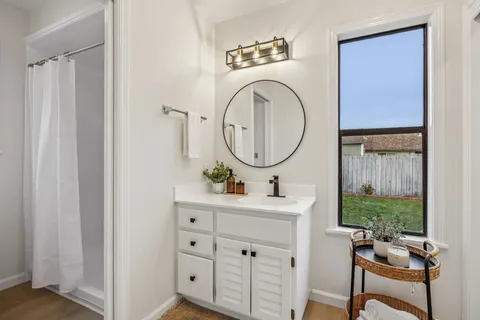 a room with a sink a mirror and a window