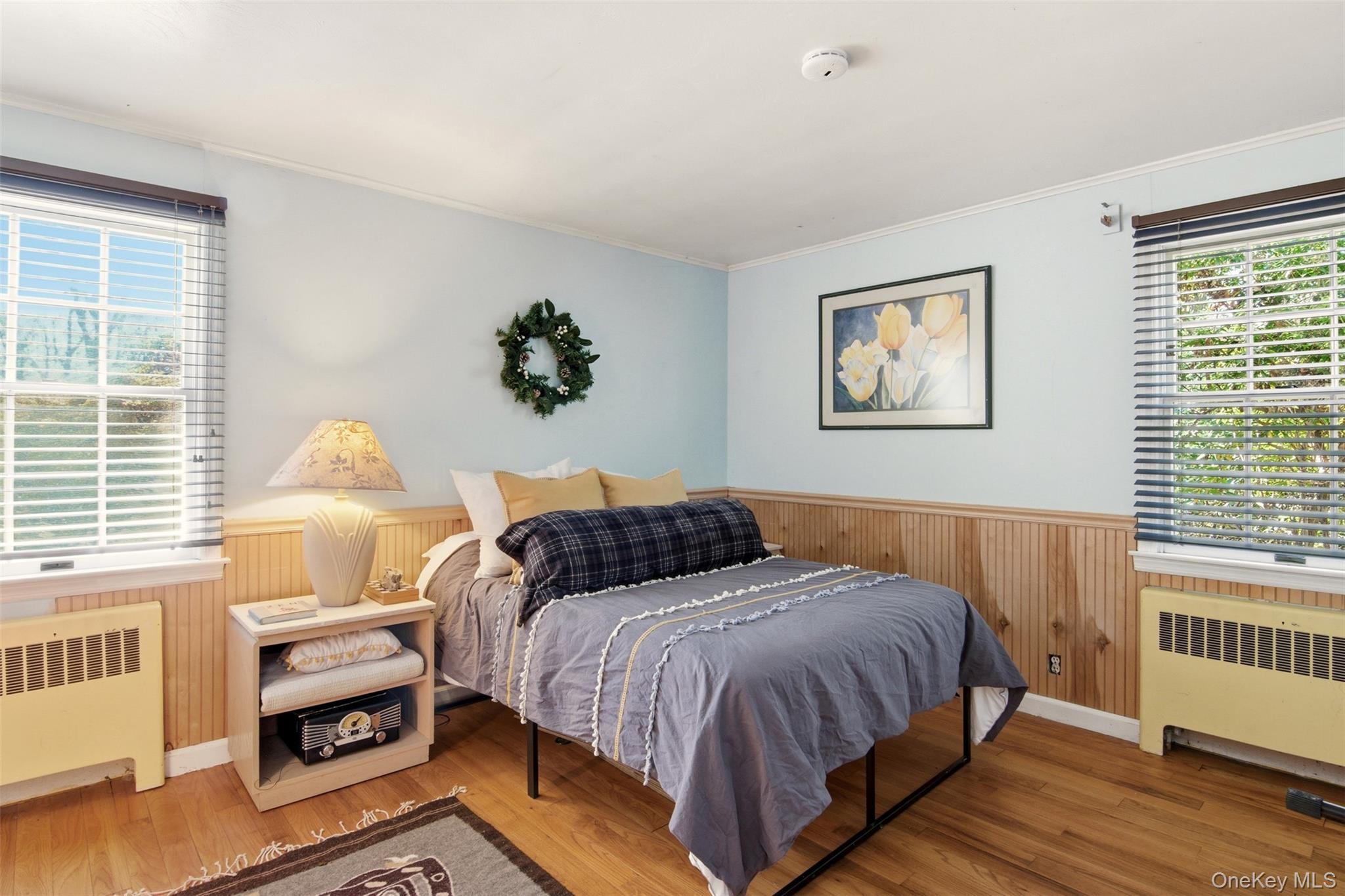 8 Old Wood Road Stony Brook, NY 11790 - Photo 13 of 50 Bedroom with multiple windows, wainscoting, wood walls, radiator, and wood-type flooring
