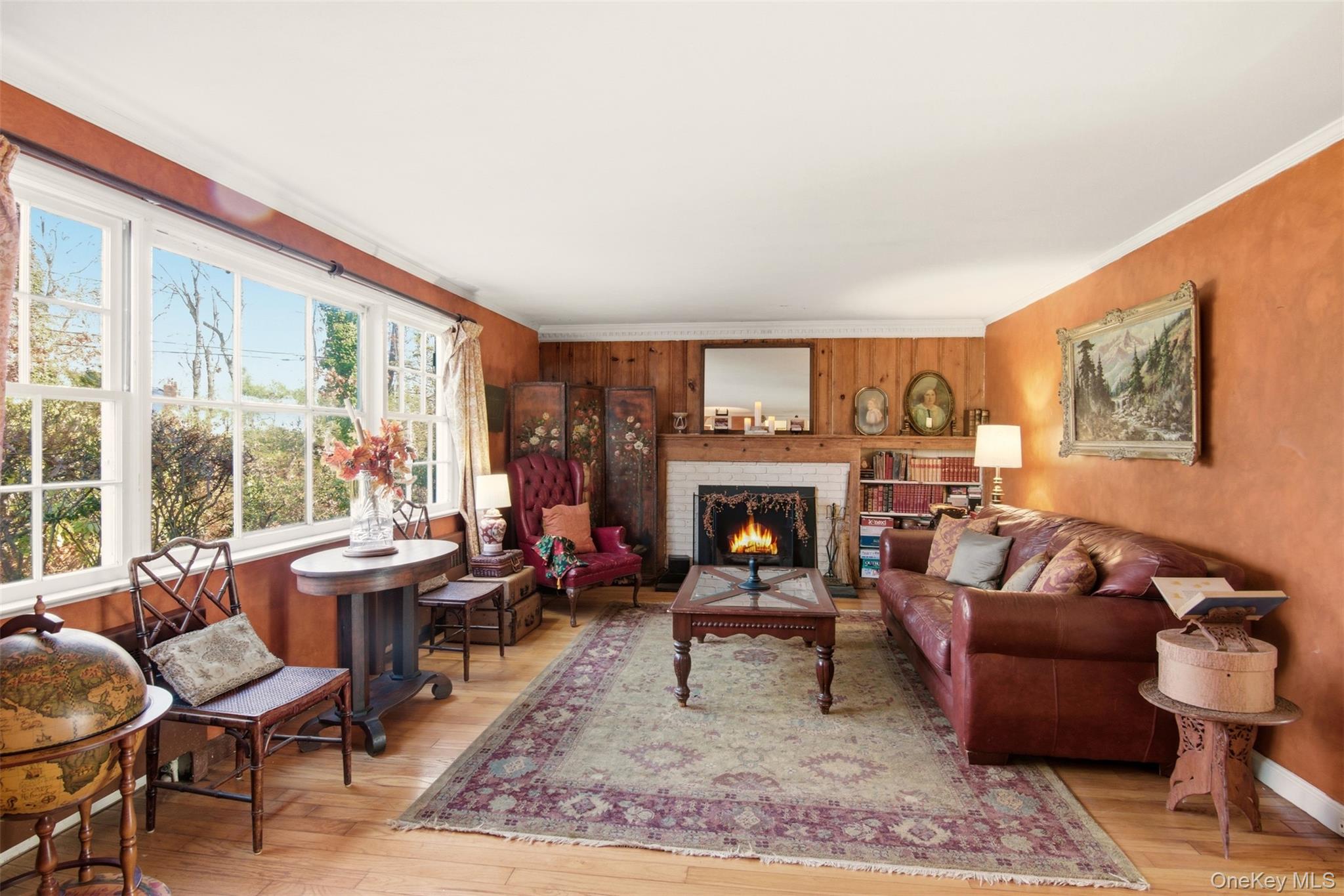 8 Old Wood Road Stony Brook, NY 11790 - Photo 4 of 50 Living room with a brick fireplace, wood-type flooring, ornamental molding, and wood walls