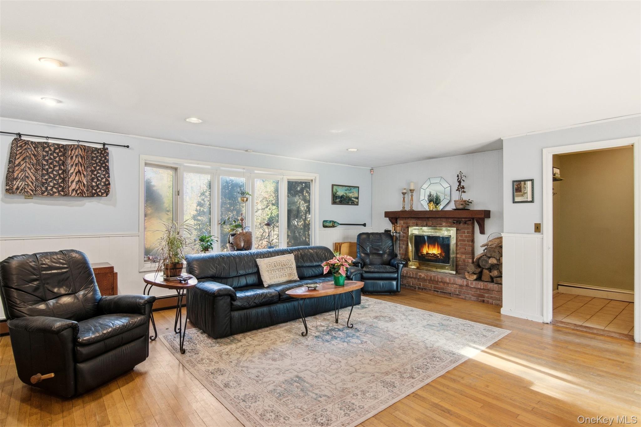 8 Old Wood Road Stony Brook, NY 11790 - Photo 8 of 50 Living room with a brick fireplace, light wood-style floors, and a baseboard heating unit
