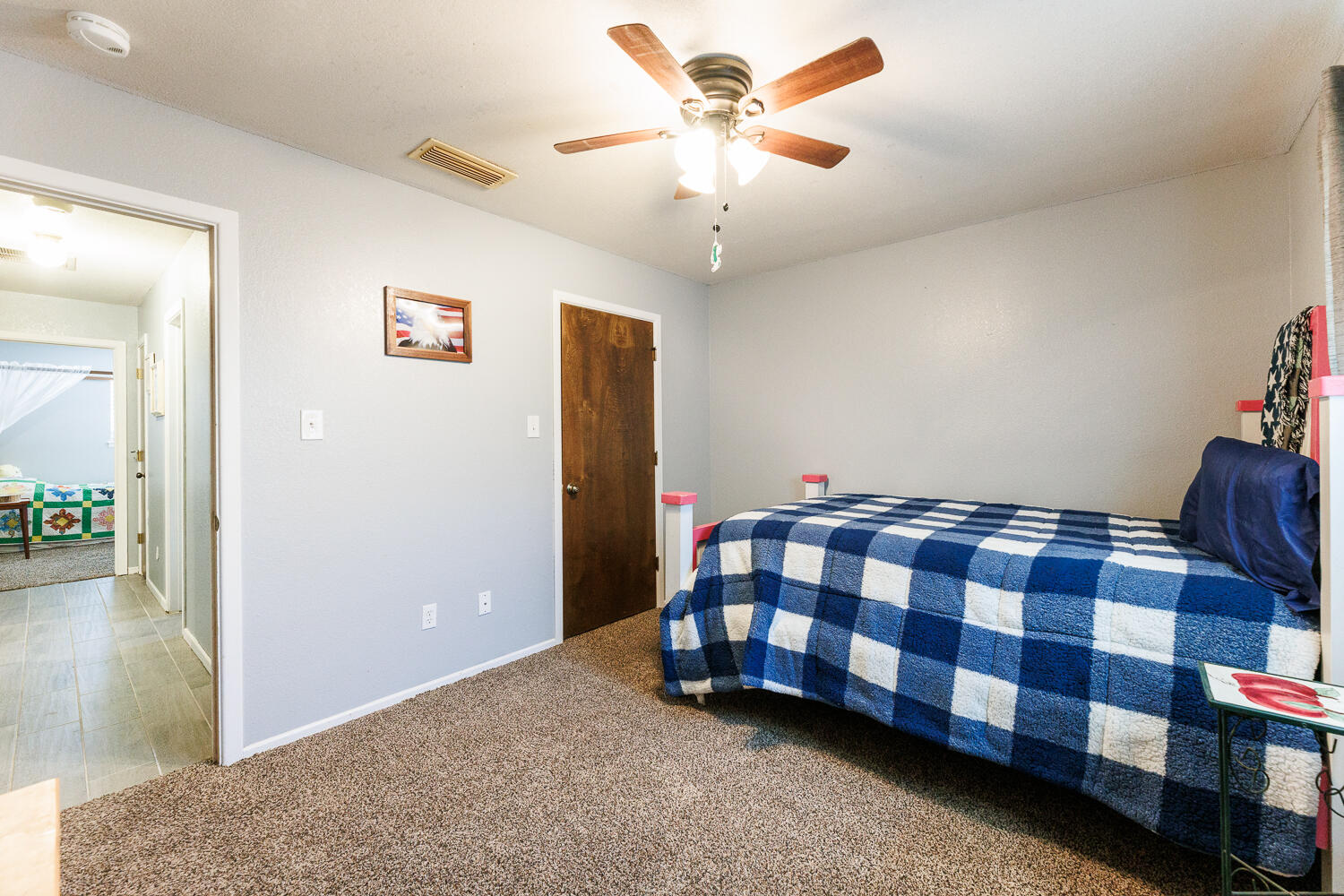 705 Grace Street Brownfield, TX 79316 - Photo 35 of 43 a spacious bedroom with a bed and a chandelier