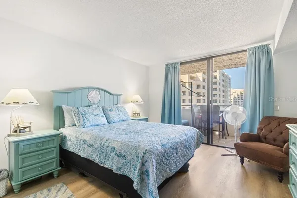 a spacious bedroom with a bed a mirror and a large window