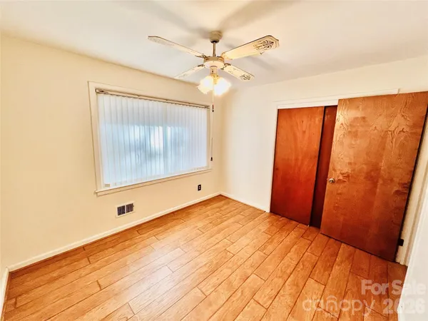 a view of a room with a ceiling fan and wooden floor